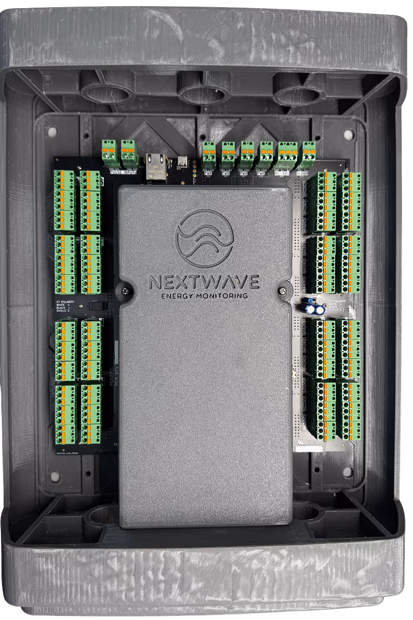 NextWave energy monitoring device inside a gray enclosure with multiple green terminal blocks and electronic components.