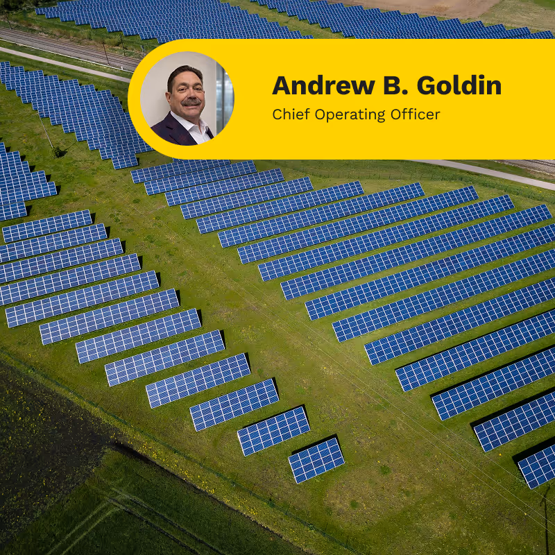 Aerial view of a solar panel farm on green grass with a yellow banner showing a man's photo and the text Andrew B. Goldin, Chief Operating Officer.