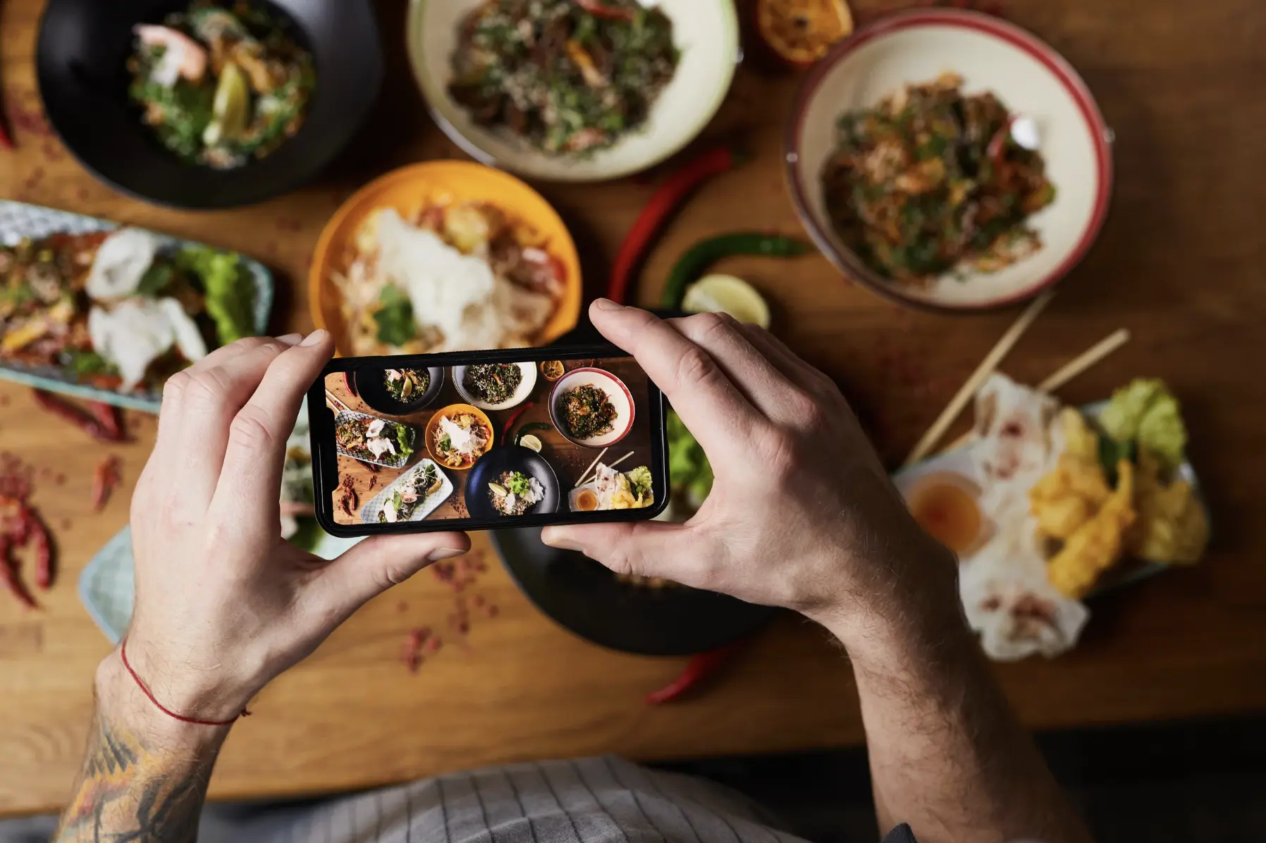 Overhead shot of a person photographing colorful dishes with a smartphone for social media marketing.
