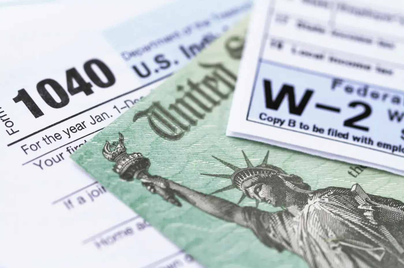 "A close-up of tax forms, including Form 1040 and W-2, alongside a U.S. Treasury check."