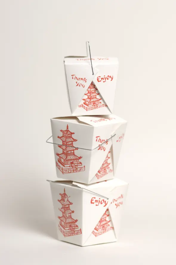 Stack of traditional white Chinese takeout boxes with red pagoda design and wire handles.
