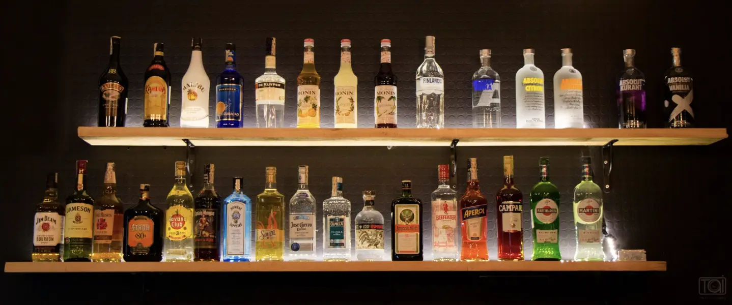 A well-lit liquor shelf with a variety of spirits, emphasizing barback responsibilities like restocking and inventory management.