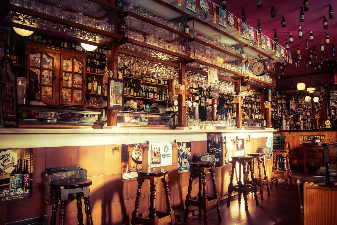  A traditional bar setup with shelves stocked with liquor, glassware, and bar essentials, showcasing a well-organized workspace.