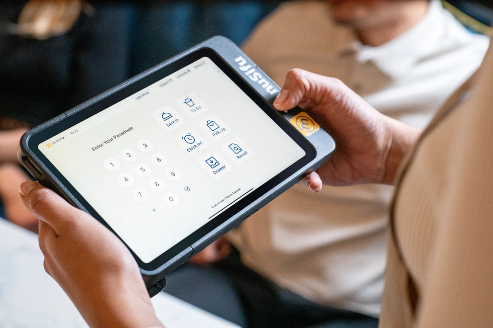 Restaurant employee using MenuSifu POS Pay Pad 2 to access clock-in, tableside ordering, and restaurant POS functions