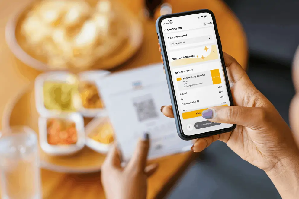 Customer using Apple Pay on a smartphone to complete a restaurant order after scanning a QR code at the table.