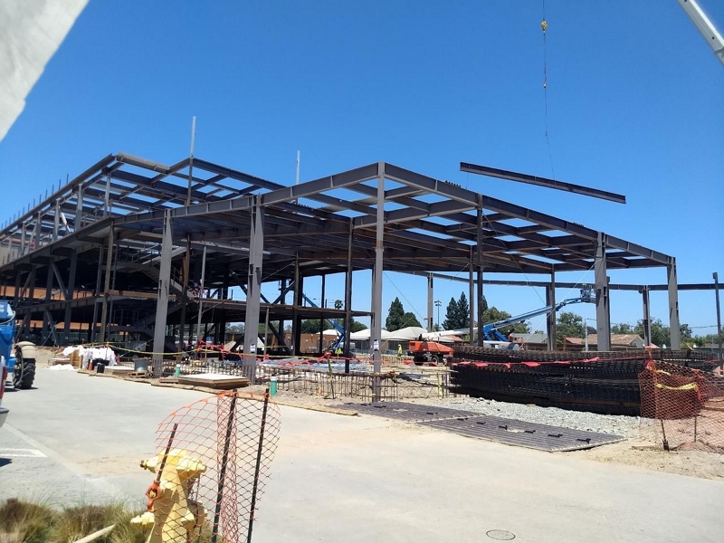 Steel-framed building under construction, showing erected structural steel, open floor levels, and construction materials at the job site