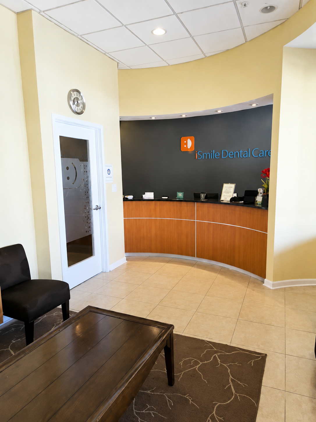  iSmile Dental Care reception and waiting area in Fairfax, VA, with a curved front desk and clinic logo on the wall.