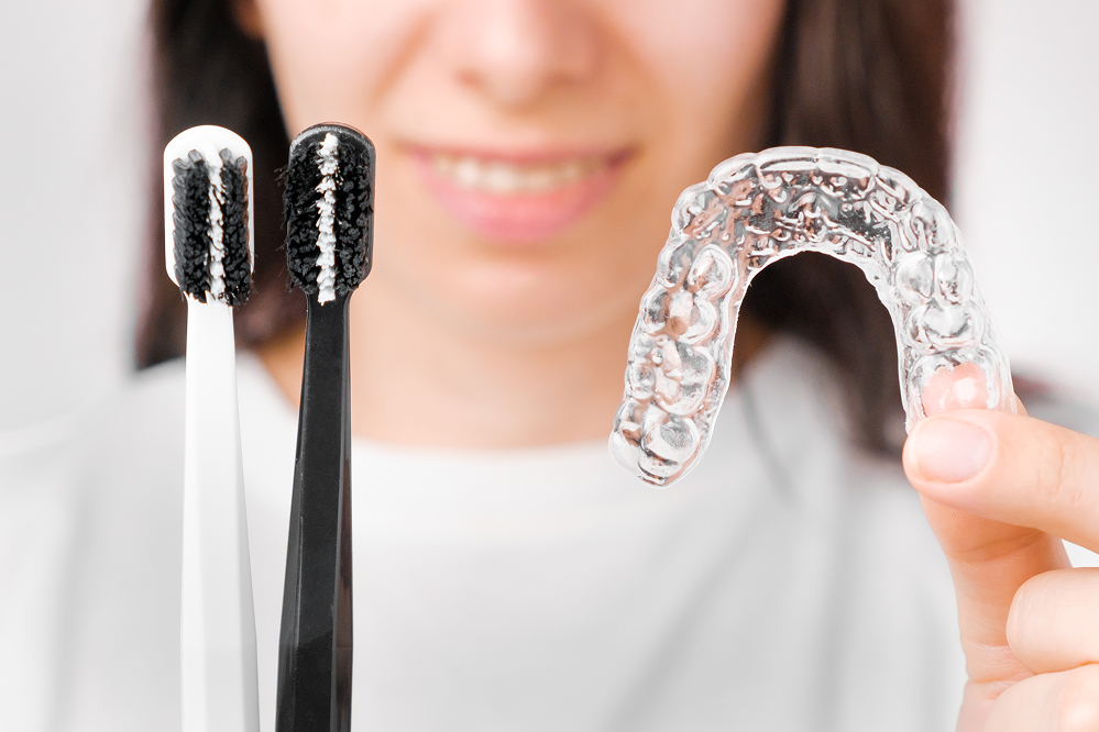 Close-up of toothbrushes next to a clear dental aligner for daily oral care