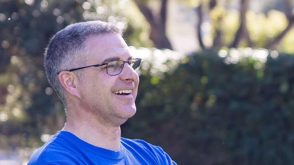 Closeup of Kevin smiling with trees in the background