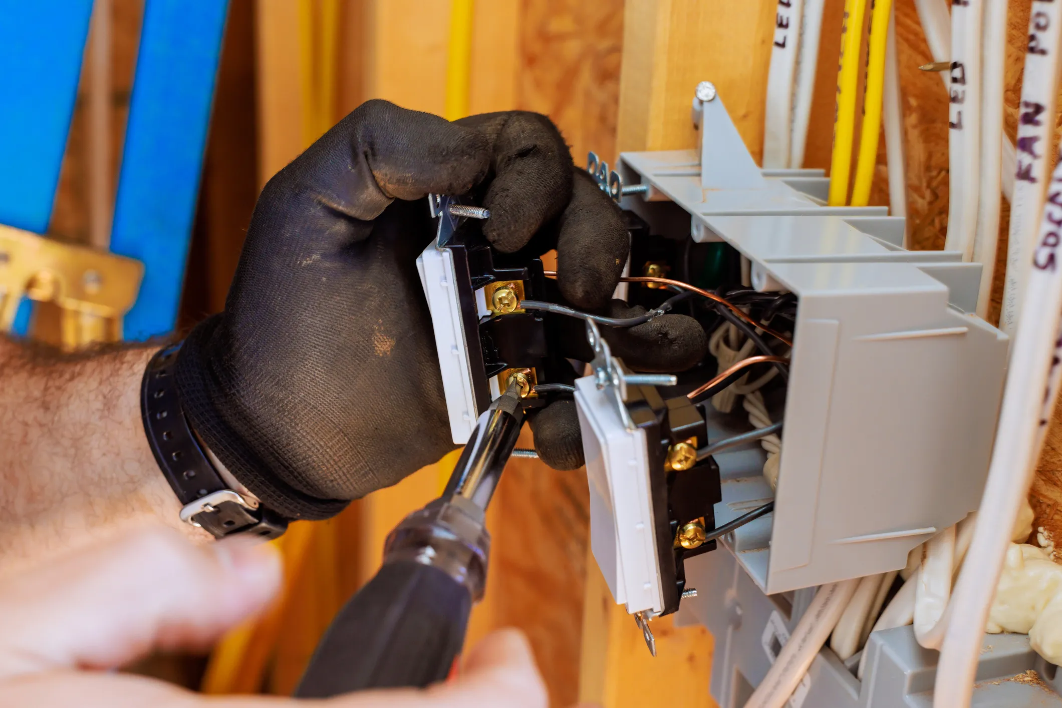 Electrician installing a Level 2 EV charger in a residential garage, connecting wiring to a modern electrical panel