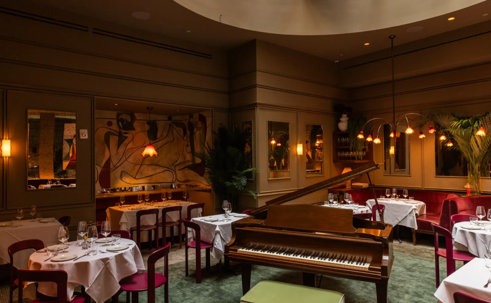 The dining room at Brass, The Evelyn, New York, with a grand piano and set tables