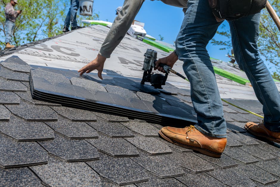 Roofing professional installing shingles on a sloped roof using a nail gun, showcasing precision in roof repair services for leak prevention.