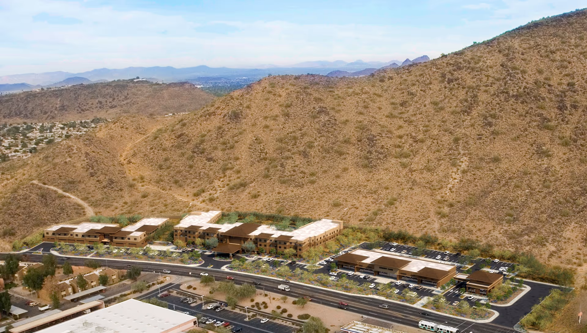Aerial view of a suburban neighborhood with houses, a parking lot, and a large brown hill under a partly cloudy sky.