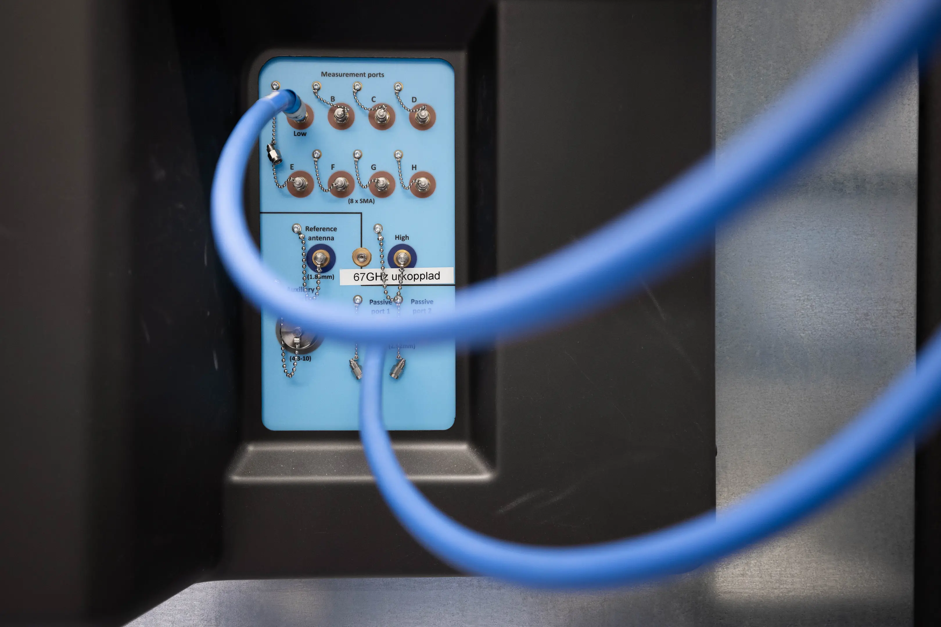 Blue network cables connected to a panel with labeled measurement ports and antennas.