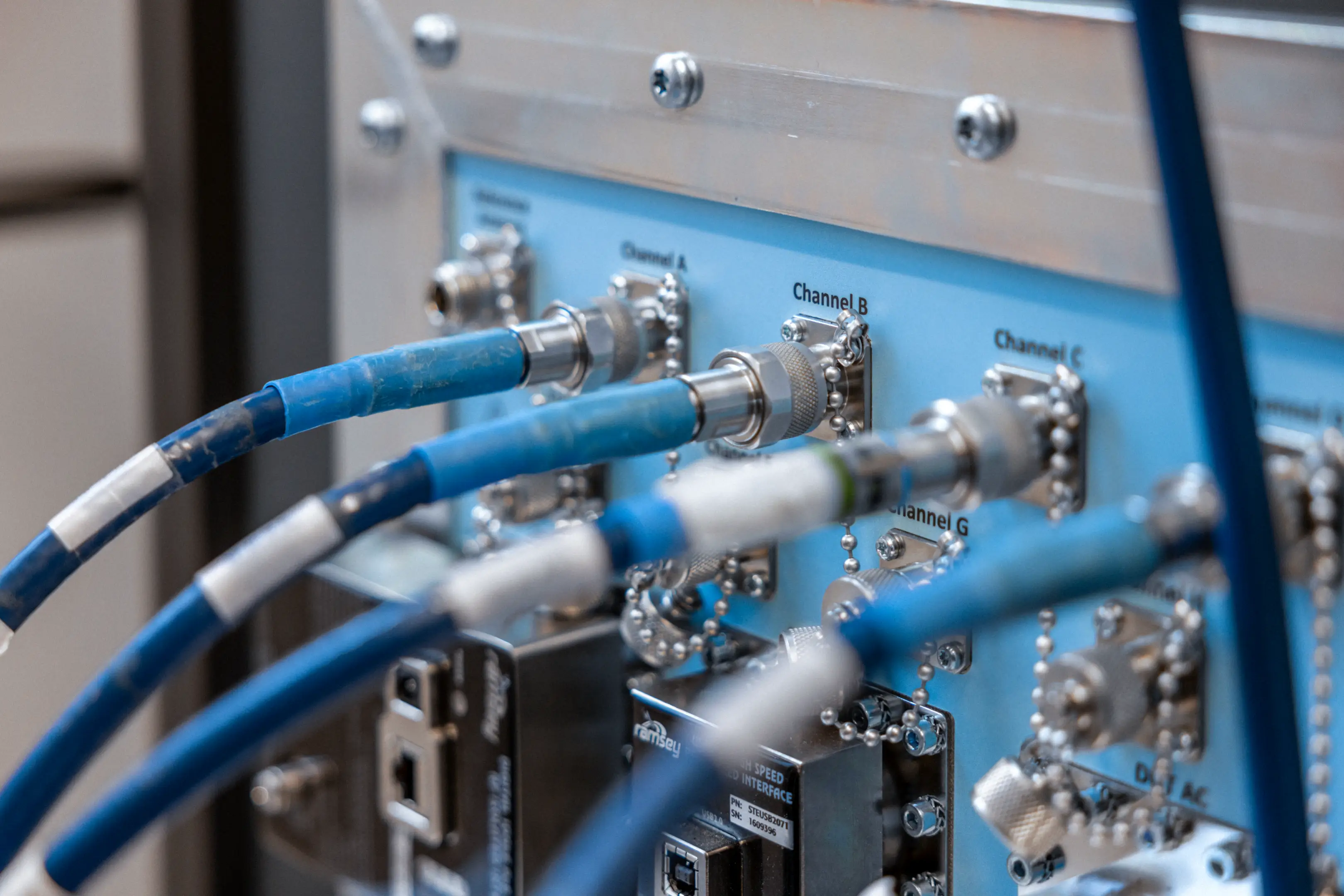 Close-up of blue cables connected to labeled metal ports on a high-speed communication interface panel.