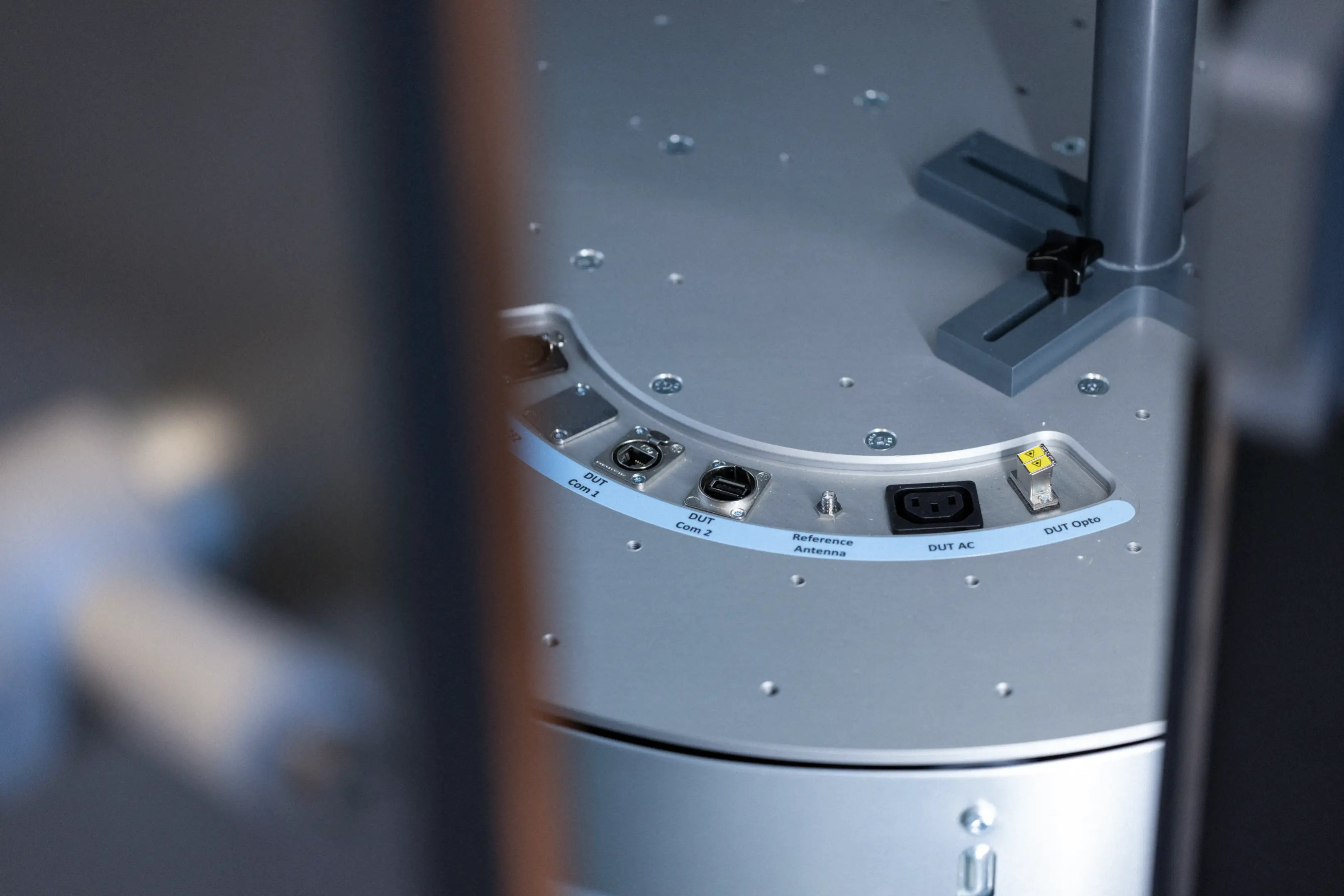 Close-up of a metal panel with labeled ports including DUT Com 1, DUT Com 2, Reference Antenna, DUT AC, and DUT Opto.