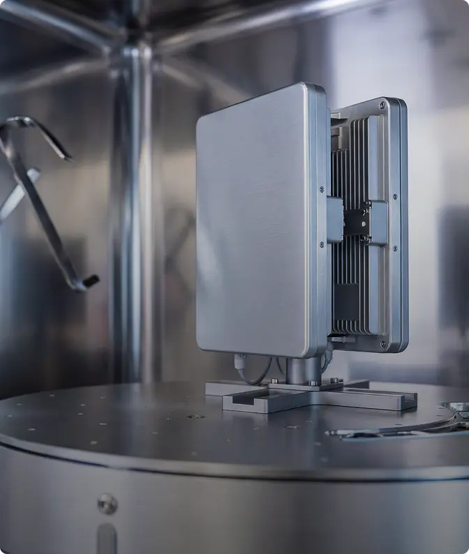 Modern rectangular metallic communication device with cooling fins mounted on a metal platform inside an industrial environment.