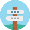 Wooden signpost with two blank white directional arrows against a blue sky and green hill background.