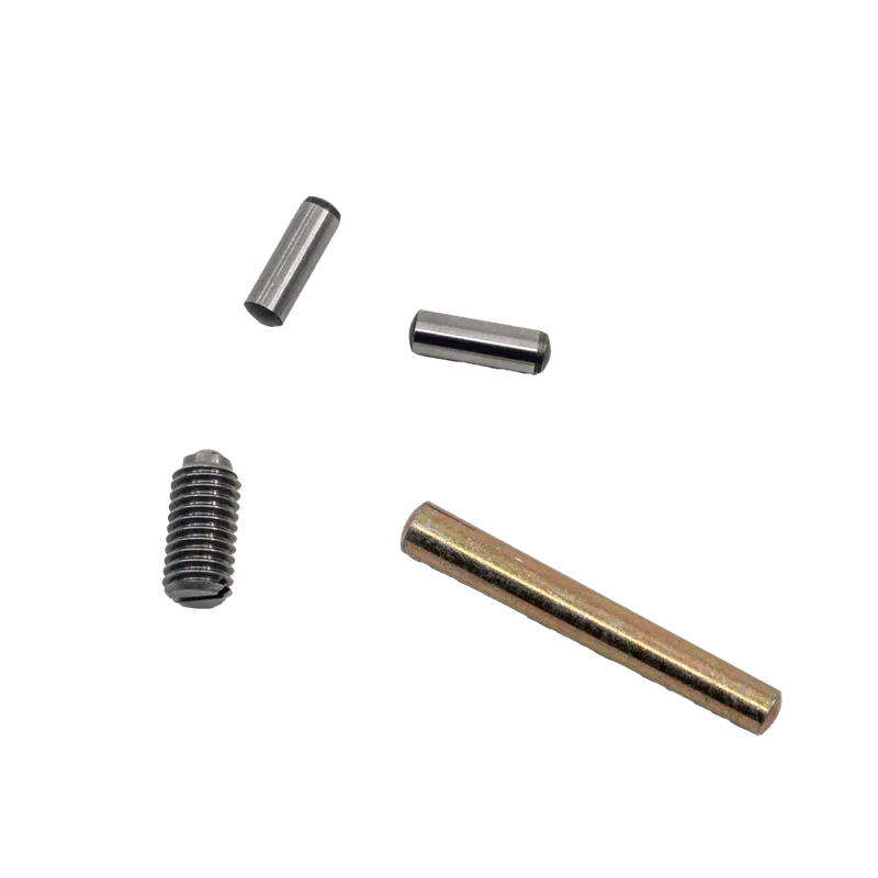 Four small metallic cylindrical machine parts on a light gray surface, including one with external threading.