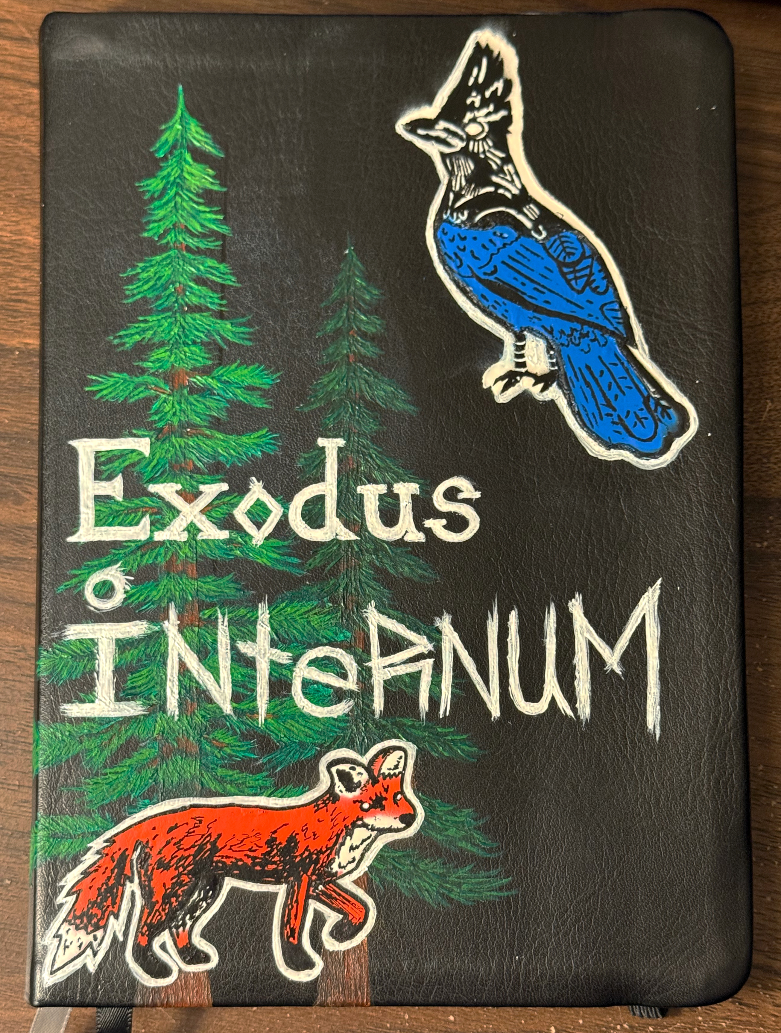 Black cover featuring green pine trees, a blue bird, an orange fox, and the white text 'Exodus Internum'.