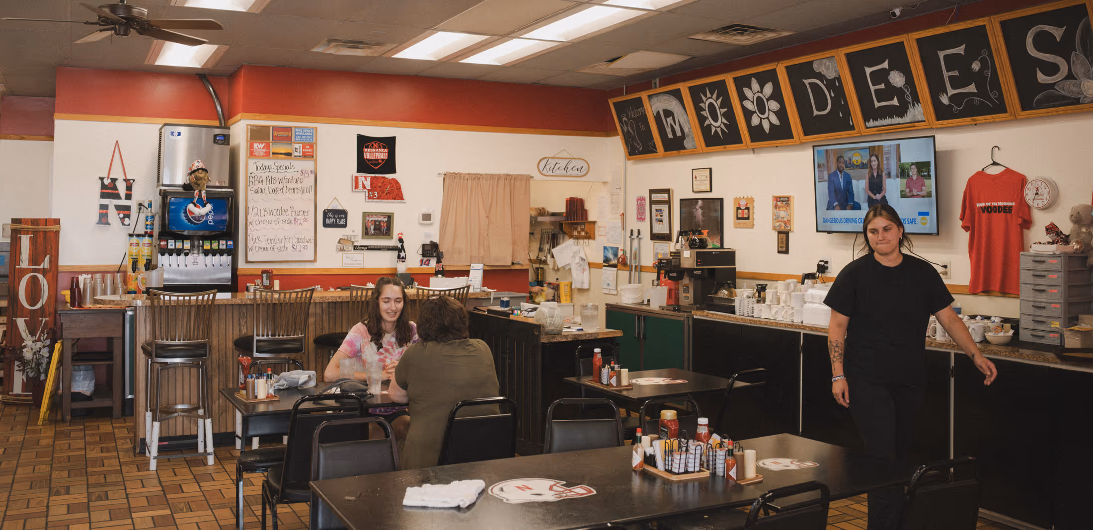Interior of Woodee’s diner with customers dining and staff behind the counter.