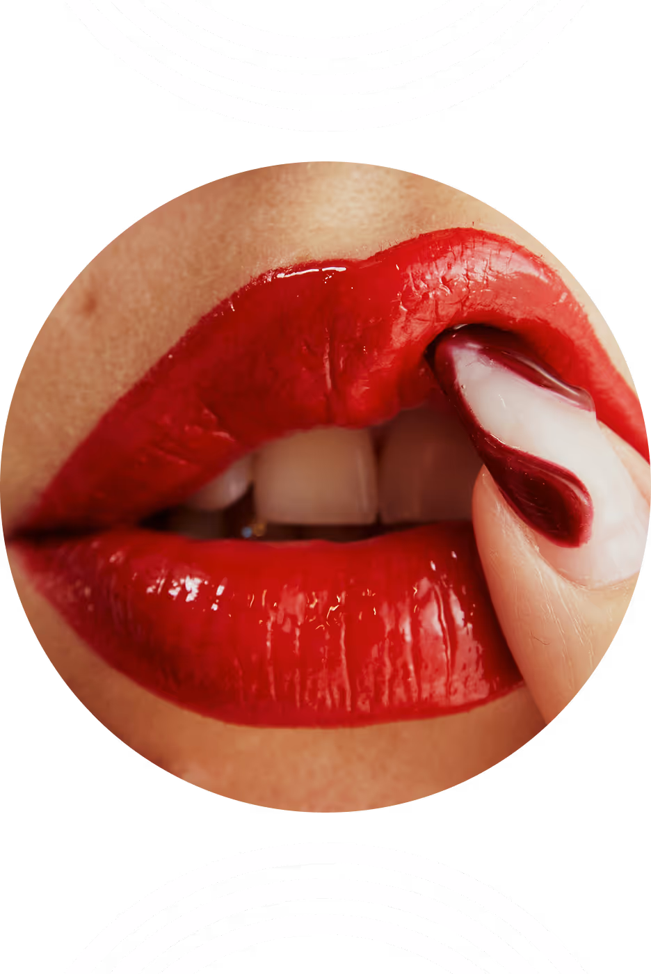 Close-up of glossy red lips with a nail painted in red and white touching the lower lip.