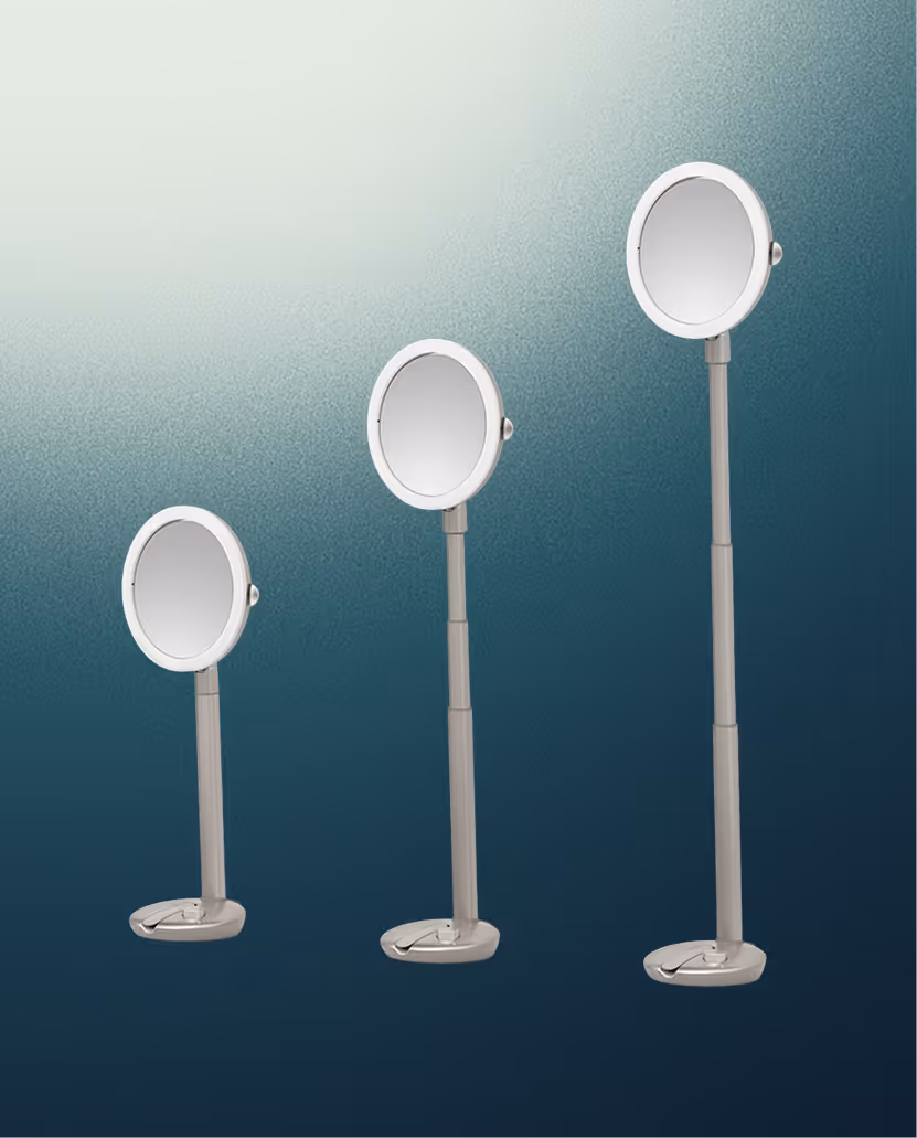 Three adjustable standing MoGlow mirrors of different heights with round reflective surfaces and foldable bases against a gradient blue background.