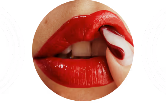 Close-up of lips with glossy red lipstick biting a nail painted with white and red swirls.