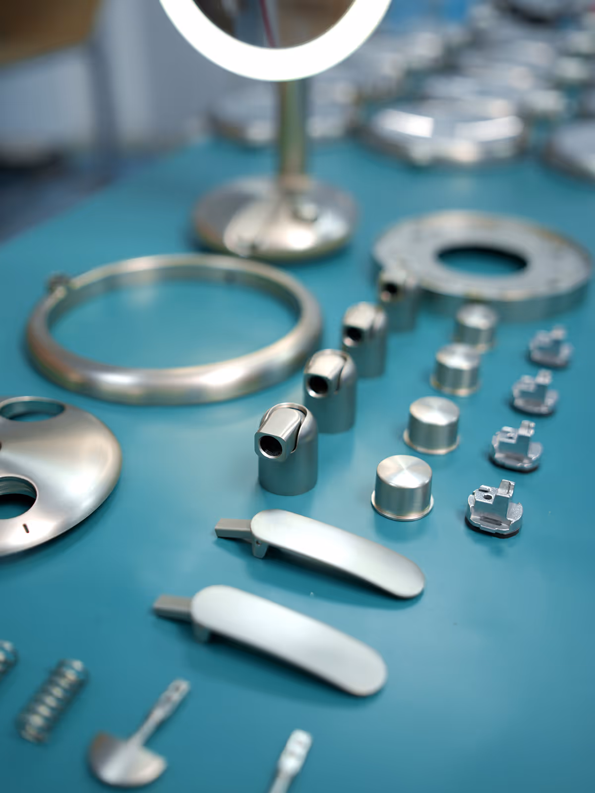 Various small metal machine parts arranged on a teal surface.