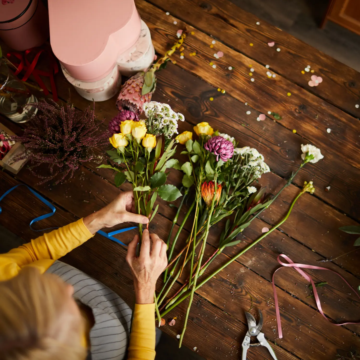 Mains de fleuriste en train de composer un bouquet de fleurs variées pour un cadeau à Genève avec livraison de fleurs dans toute la Suisse
