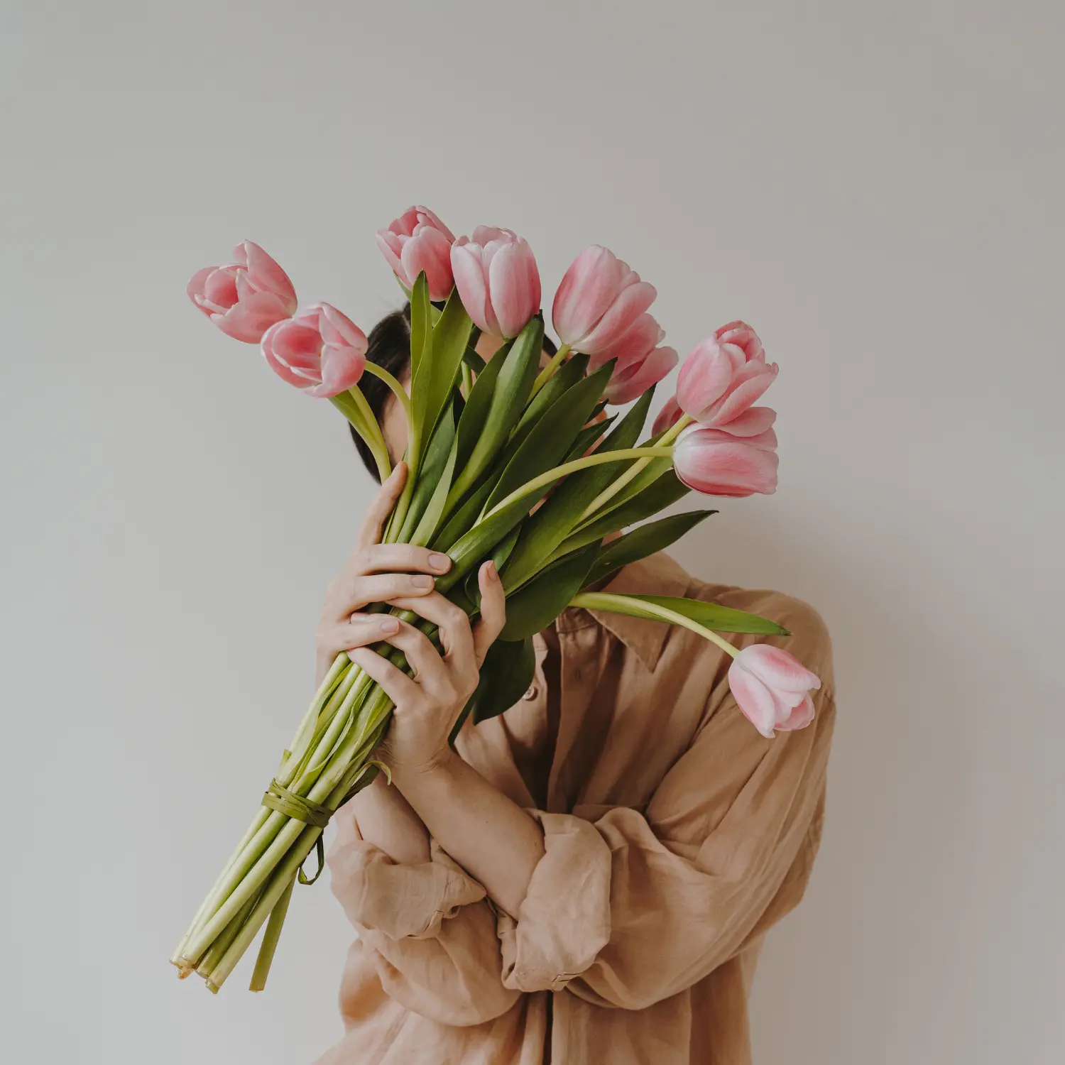 Personne tenant un bouquet de tulipes roses, idée cadeau douce et moderne à Genève avec livraison de fleurs dans toute la Suisse