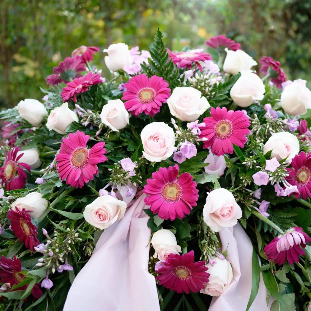 Couronne de deuil rose et blanche avec gerberas et roses et ruban blanc pour un hommage floral à Genève avec livraison de fleurs dans toute la Suisse