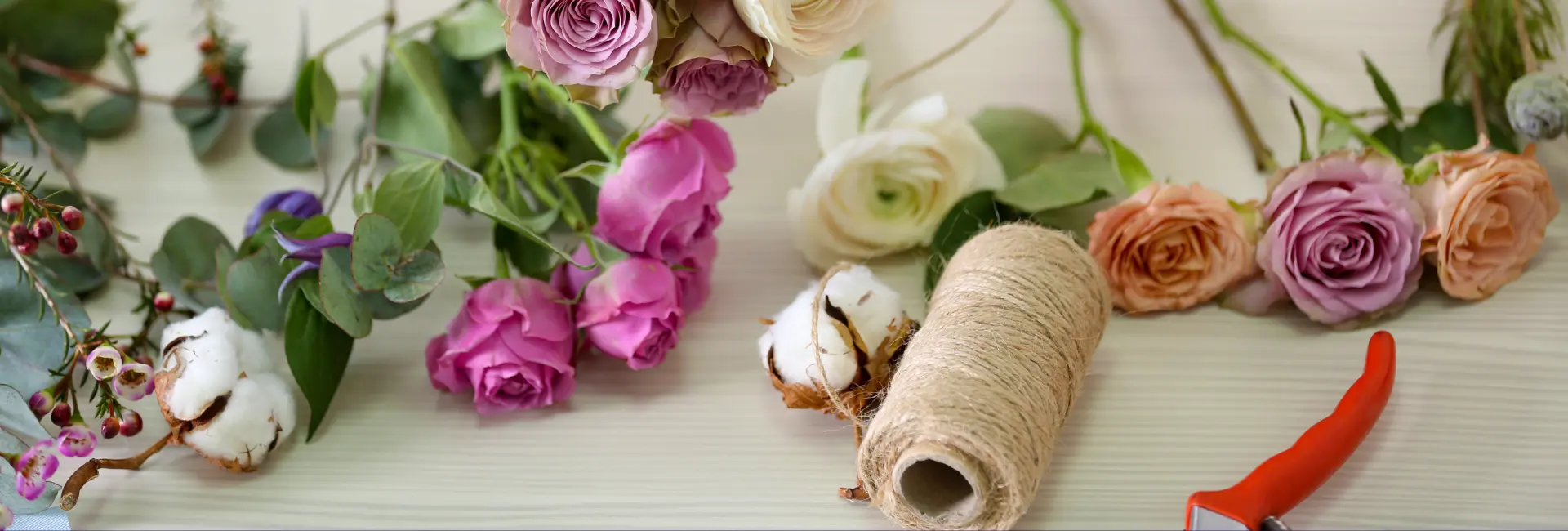 Plan de travail de fleuriste avec fleurs fraîches ciseaux et ficelle pour la préparation de bouquets à Genève avec livraison de fleurs dans toute la Suisse