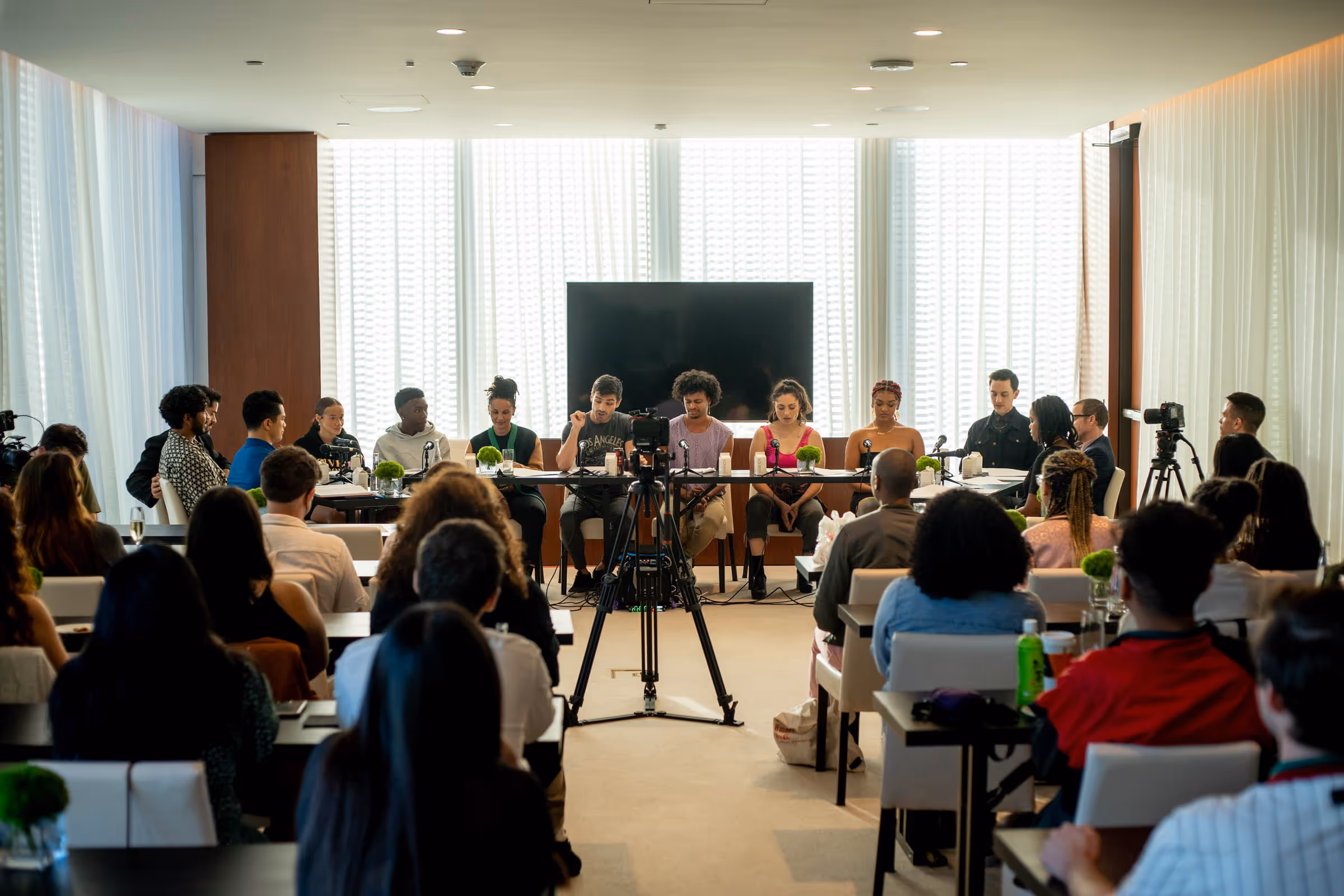a group of people sitting at a table in front of a large group of people