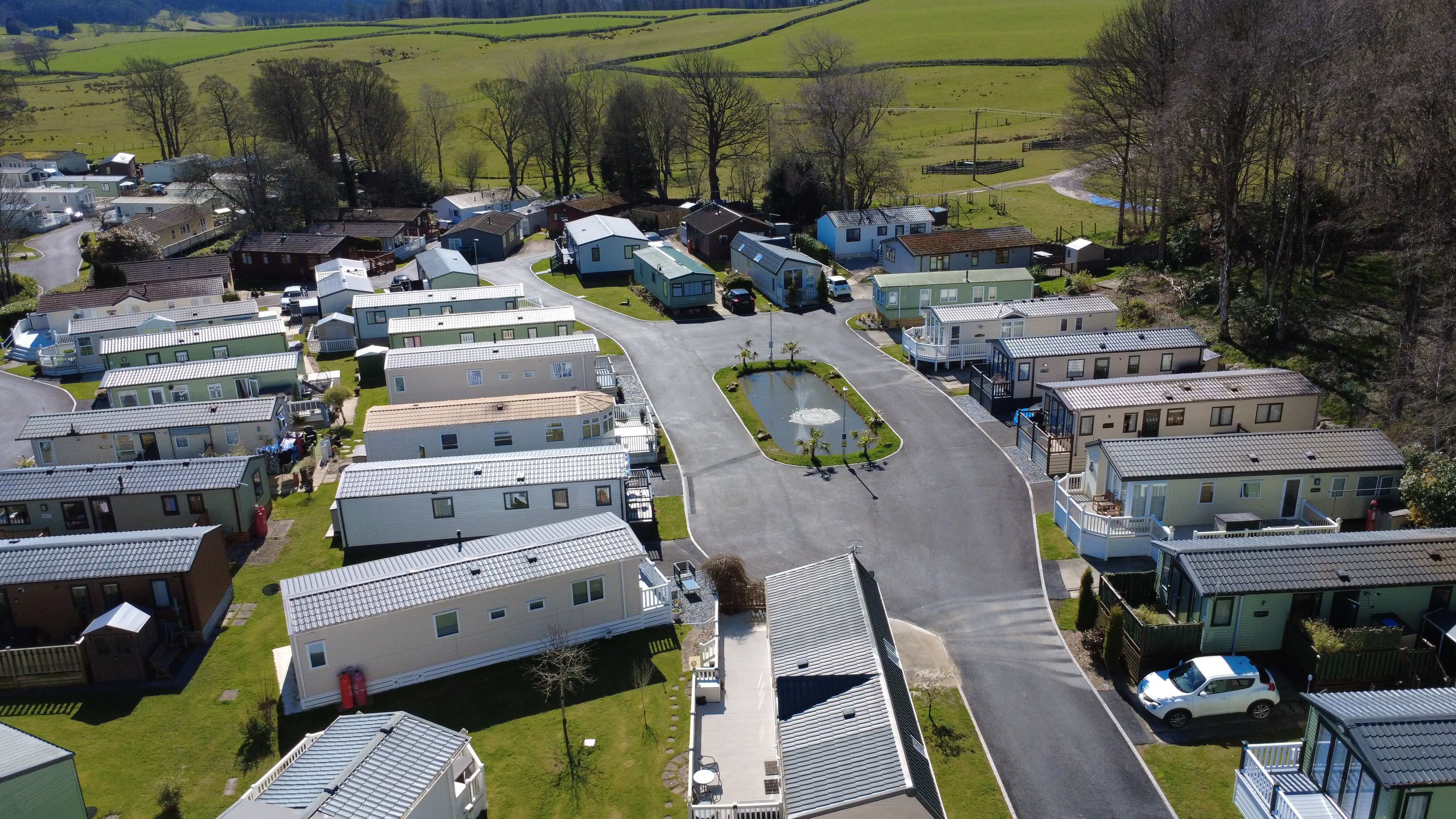 Aerial view of mobile home park with green fields and trees in background