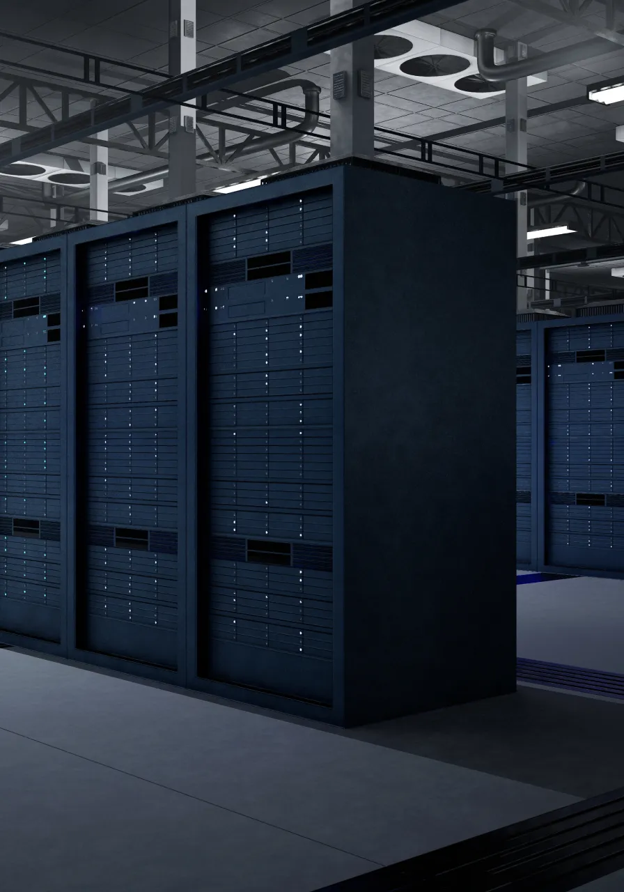 Rows of black server racks in a modern data center with overhead ventilation pipes and lighting.