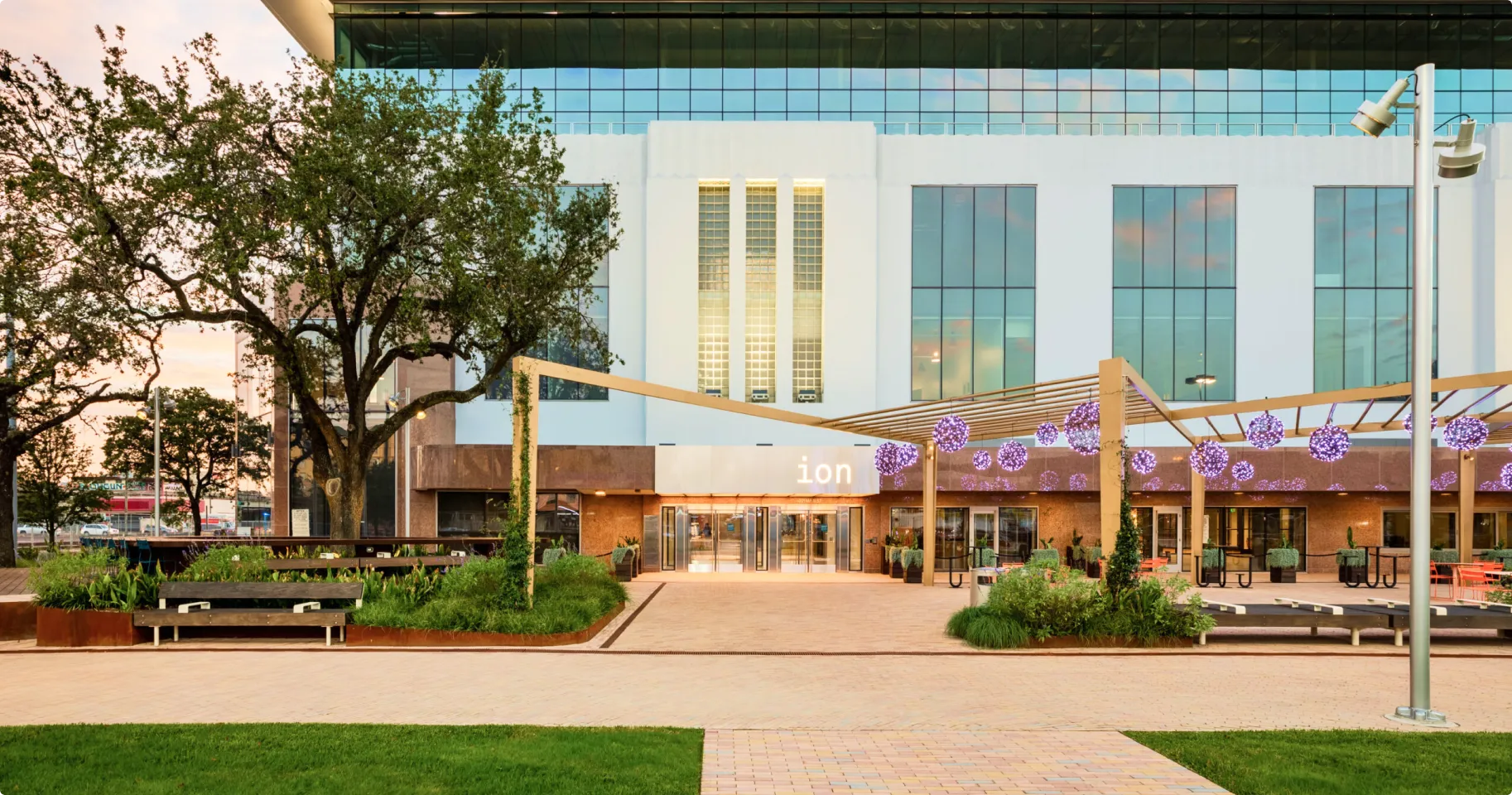 ZettaJoule Houston office entrance at the Ion building, a modern glass-and-brick facility with landscaped courtyard and outdoor seating in Houston’s innovation district.