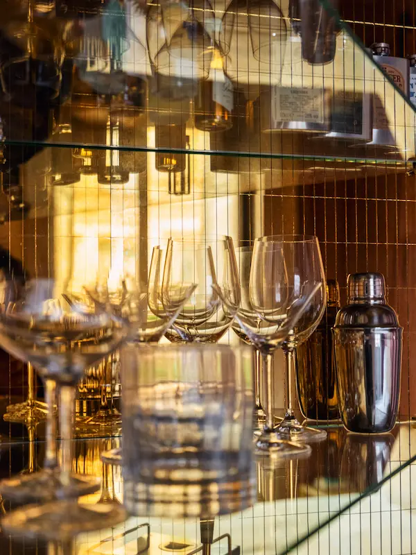 Cocktail glasses and shaker on a mirrored shelf at the Hotel Experimental Infante Sagres bar in Porto.