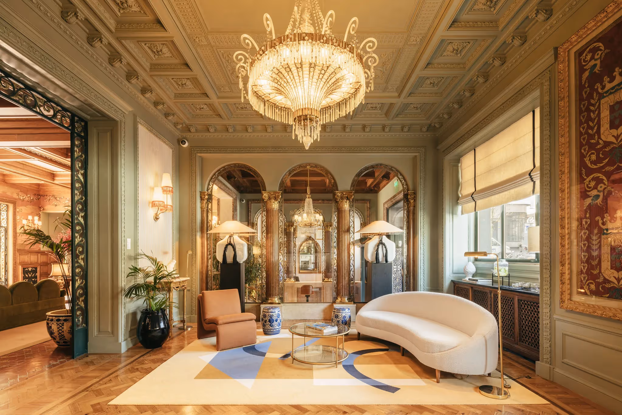 Welcome lounge of the Hotel Experimental Infante Sagres in Porto featuring a curved white sofa and crystal chandelier.