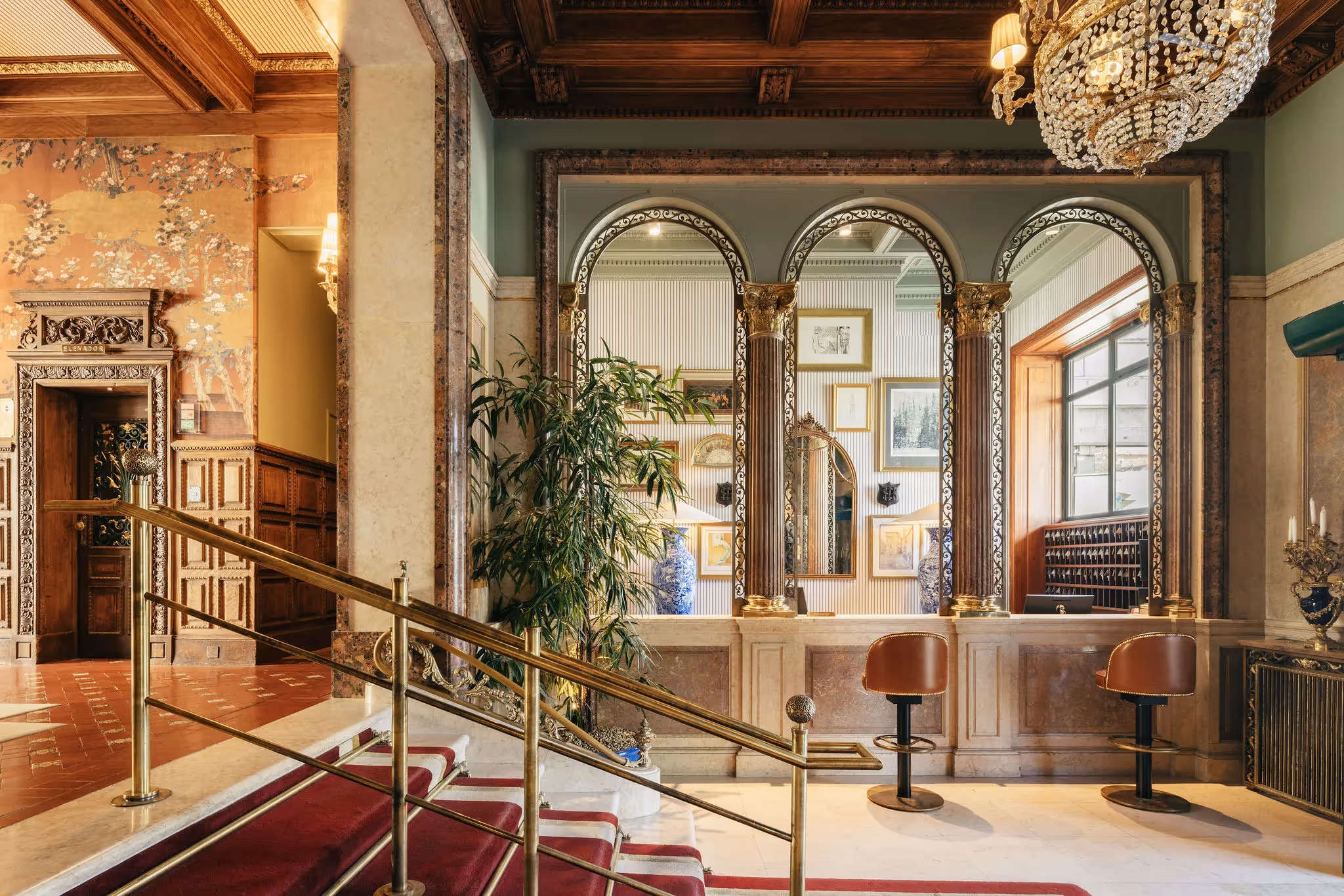 Classic concierge desk at the Hotel Experimental Infante Sagres in Porto with mirrored arches and golden columns.