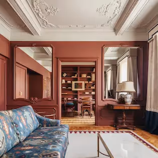 Spacious living room at Hotel Experimental Infante Sagres in Porto with blue ikat sofa, wall mirrors, and library in the background.