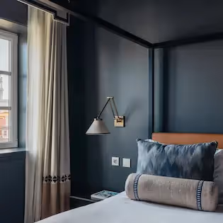 Bedroom with canopy bed and city view at Hotel Experimental Infante Sagres in Porto.