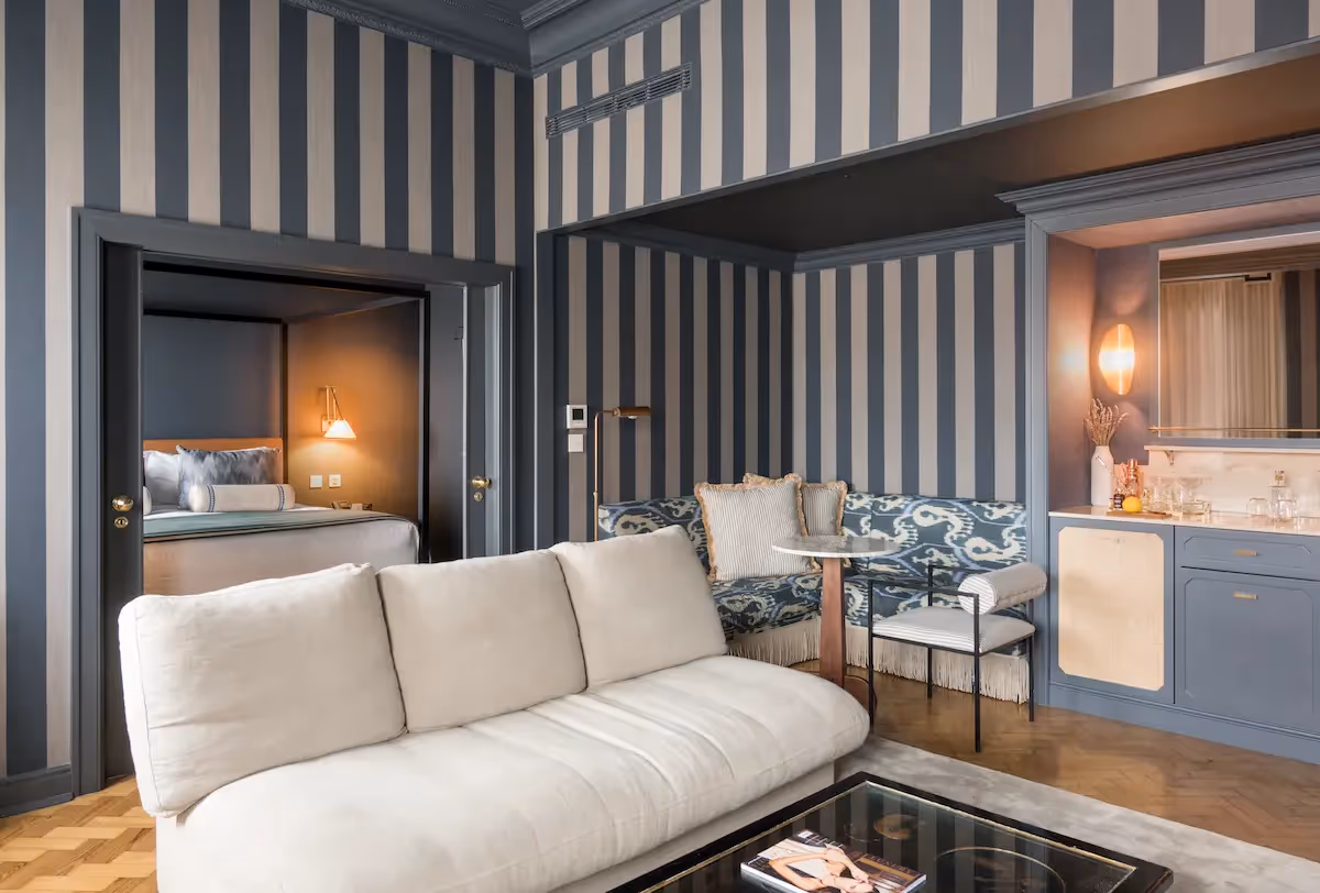Elegant suite with striped wallpaper, a seating area, and herringbone parquet flooring at Hotel Experimental Infante Sagres in Porto.