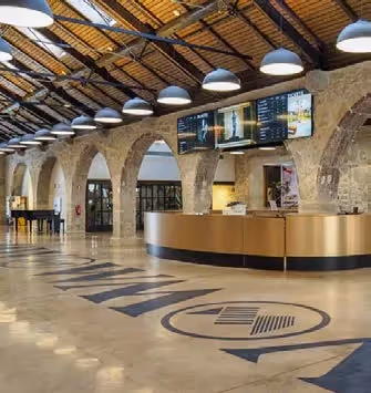 Modern reception area with stone arches and a grand piano at the Hotel Experimental Infante Sagres in Porto.
