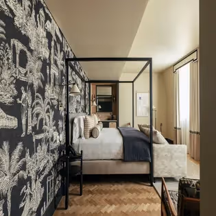 Spacious bedroom with a black canopy bed and herringbone parquet flooring at the Hotel Experimental Infante Sagres in Porto.