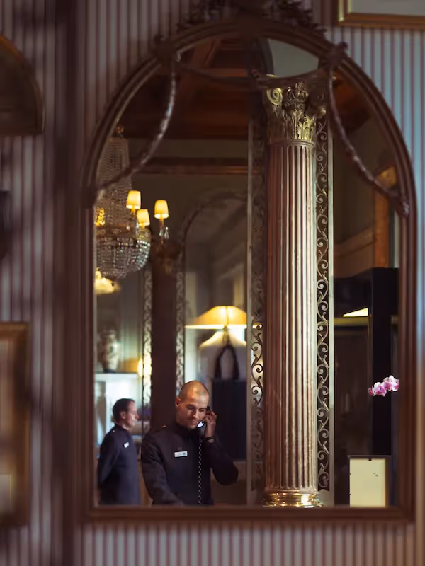 Luxurious decor and concierge service reflected in a golden mirror inside the Hotel Experimental Infante Sagres in Porto.