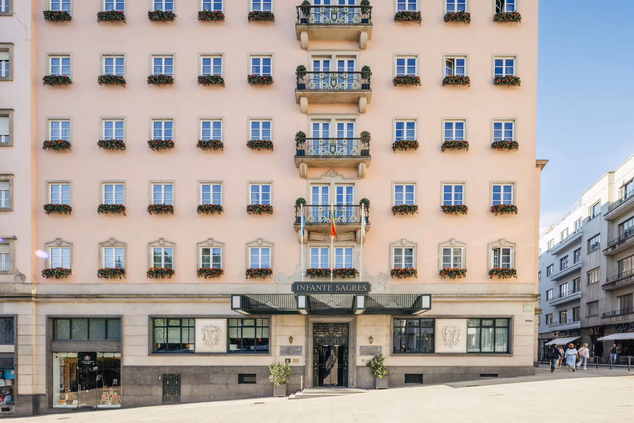 Exterior facade of the Hotel Experimental Infante Sagres in Porto featuring flowered balconies and its prestigious entrance.
