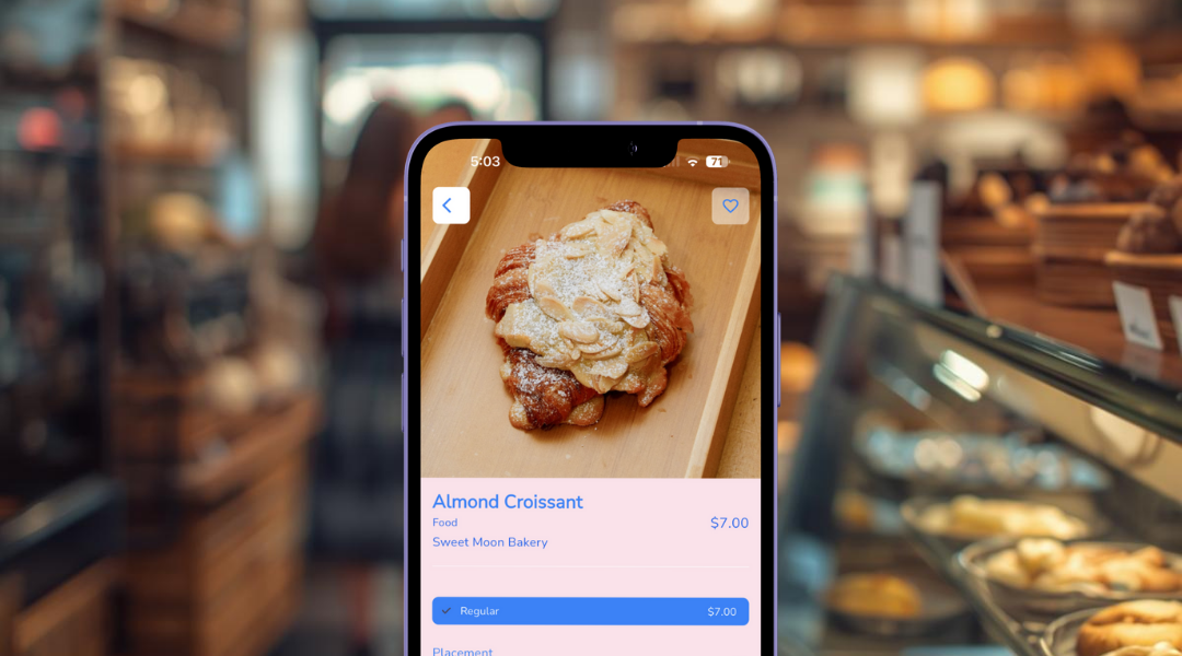 Smartphone screen showing an online bakery order for an almond croissant priced at $7.00, with a blurred bakery background.