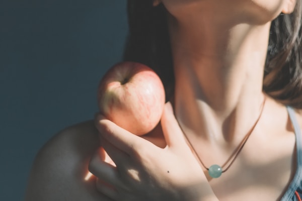 woman in silver necklace holding apple