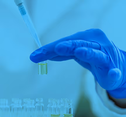 Blue gloved hand holding test tube in medical or scientific laboratory